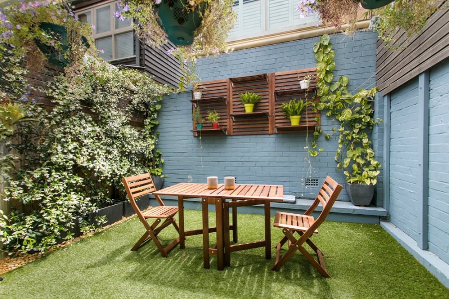 Kleine Hinterhofterrasse mit Gras und Holztisch