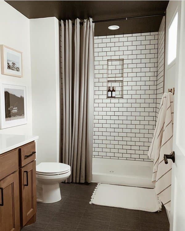 Neutral shower curtain in a modern bathroom with subway tiles and wooden vanity.