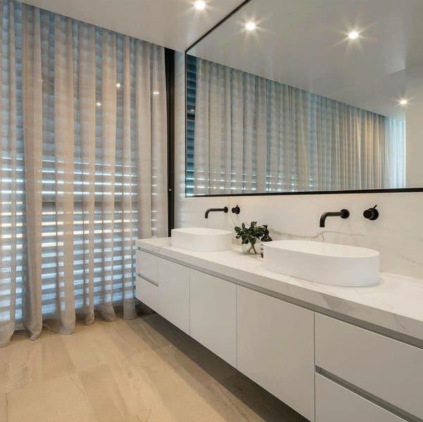 Contemporary bathroom with floor-to-ceiling sheer curtains and dual sink vanity with large mirror.