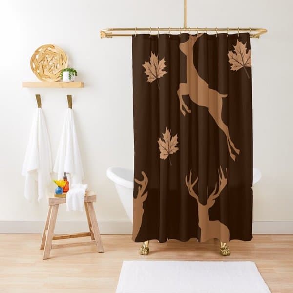 Shower curtain with deer and leaf pattern in a minimalist bathroom with white towels and stool.