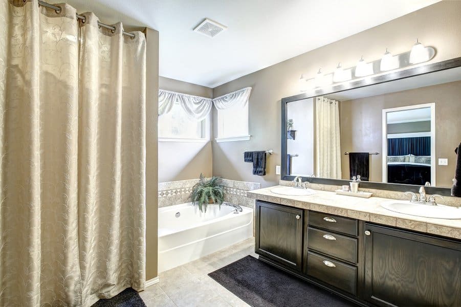 Elegant bathroom with cream shower curtain, double vanity, and soaking tub.