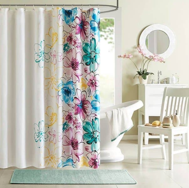 Colorful floral shower curtain with teal, pink, and yellow flowers in a bright white bathroom.