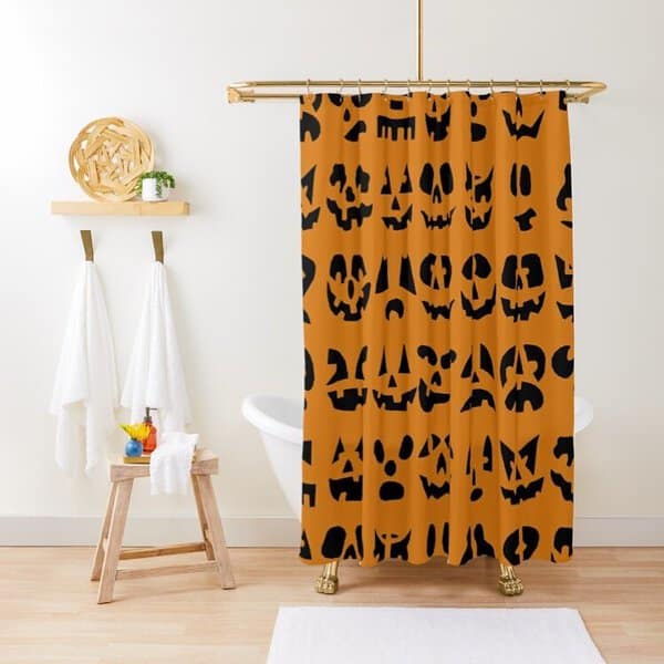 Halloween-themed shower curtain with black jack-o'-lantern faces on an orange background in a modern bathroom setting.