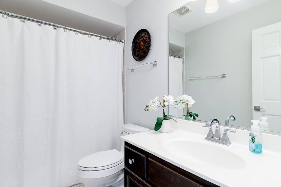 Minimalist bathroom with plain white shower curtain and dark wood vanity.