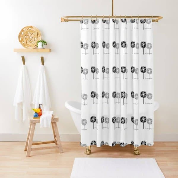 Shower curtain with black floral pattern in a minimalist bathroom with gold clawfoot tub.