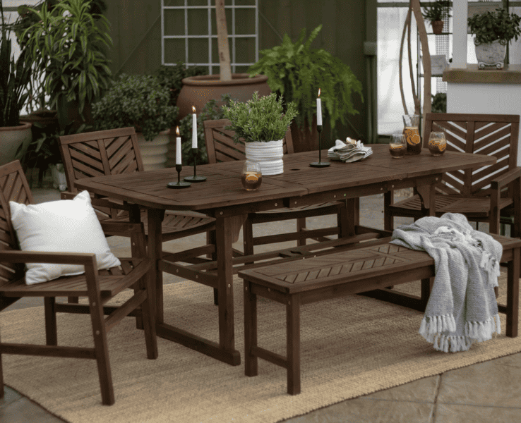 Wooden outdoor dining set with chairs, a bench, and a table decorated with candles and plants.