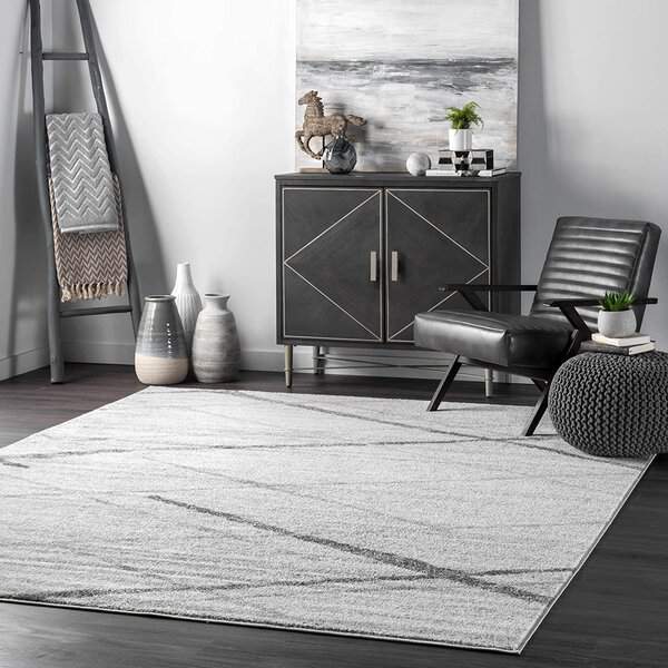 Modern living room with gray, geometric carpet, black leather chair and decorative cabinet.