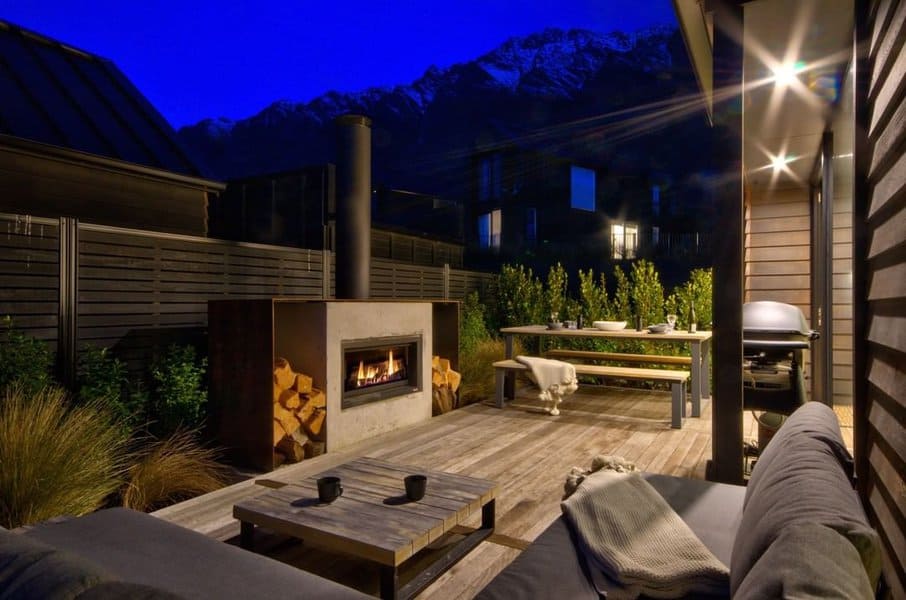 Cozy evening outdoor lounge with a modern fireplace, wooden deck, and stunning mountain views under a clear night sky