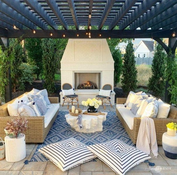 Elegant pergola-covered patio with a modern white fireplace, cozy wicker seating, and stylish accents for a serene outdoor retreat