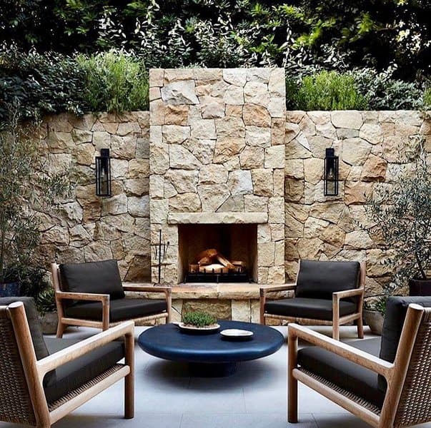 Chic stone fireplace surrounded by modern wooden chairs, creating a stylish and intimate outdoor seating area