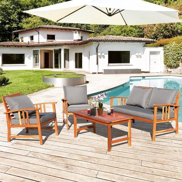 Elegant outdoor furniture set on a wooden deck by the poolside, complemented with a large white umbrella for shade and a scenic villa backdrop