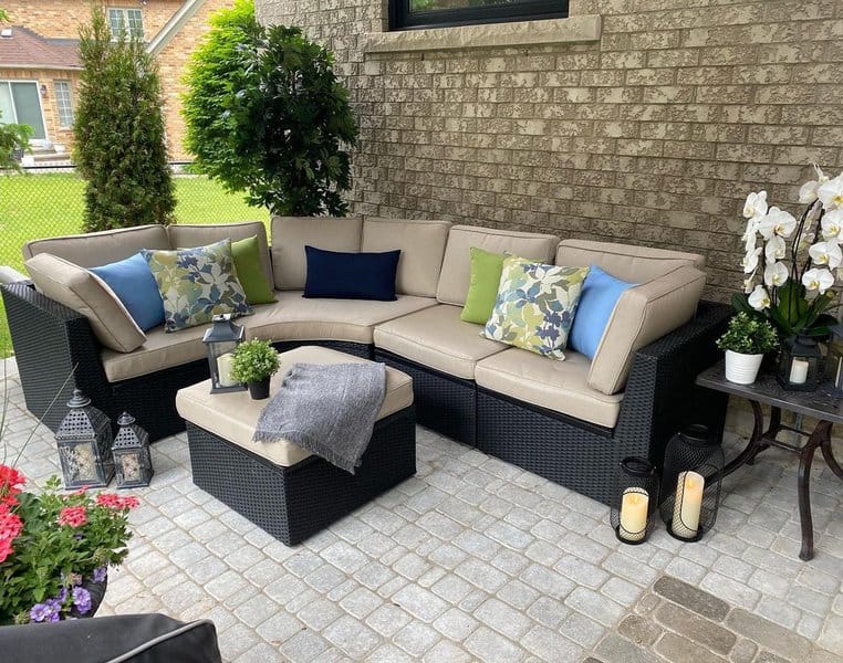 Cozy outdoor corner with a wicker sectional, colorful cushions, and lantern accents for a serene retreat.