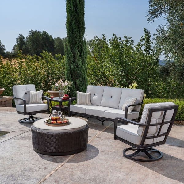 Elegant outdoor seating area with cushioned chairs, a round wicker table, and lush greenery creating a serene backyard retreat