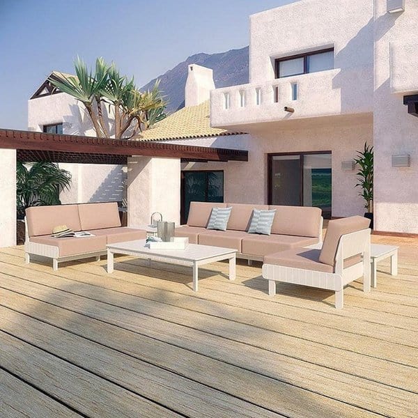 Modern patio with beige sofas and a coffee table on a wooden deck by a white house