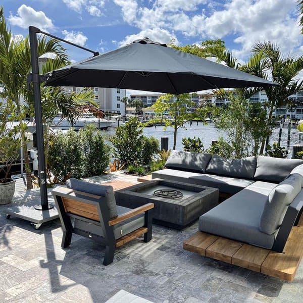 Outdoor patio with gray seating, large umbrella, and view of a marina and palm trees